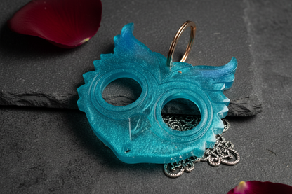 Turquoise owl keychain in subtle dark setting